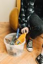 Person in Black and White Plaid Shirt and Blue Denim Jeans Sitting on Brown Leather Sofa