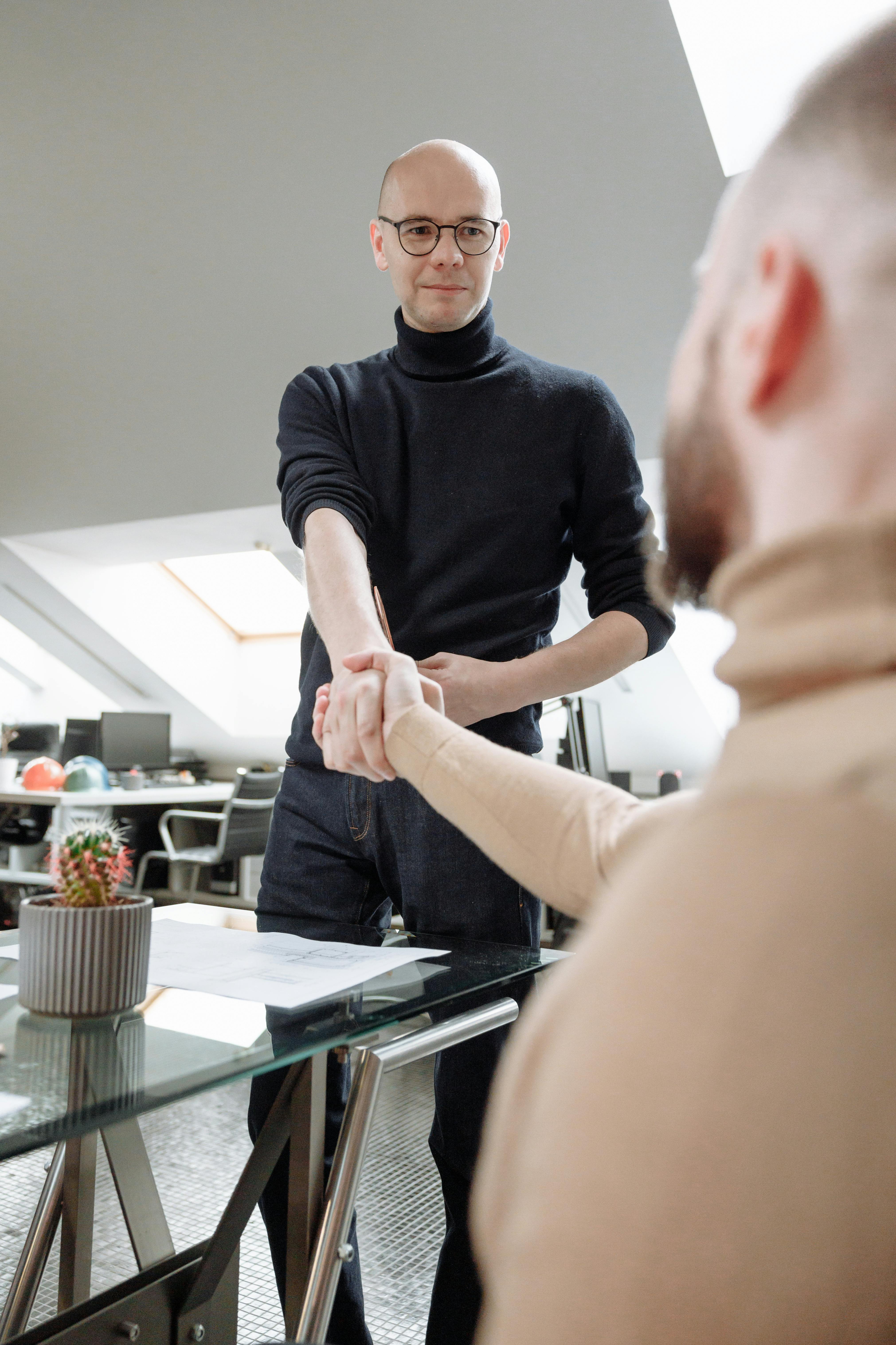 在现代化的共同工作空间中，两位专业人士握手，象征着合作