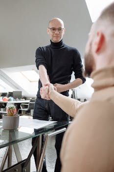 在现代化的共同工作空间中，两位专业人士握手，象征着合作