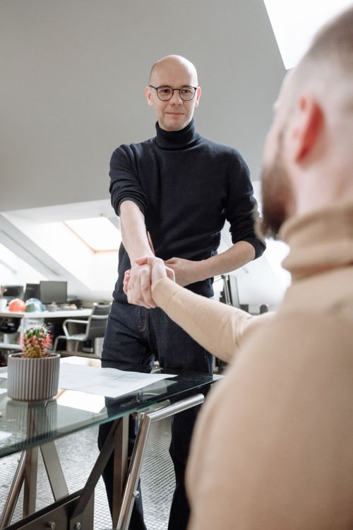Free Two professionals shaking hands in a modern coworking space, symbolizing collaboration. Stock Photo