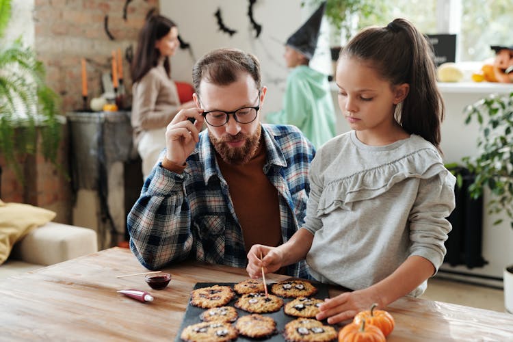 A Girl Decorating Cookies With Her Father