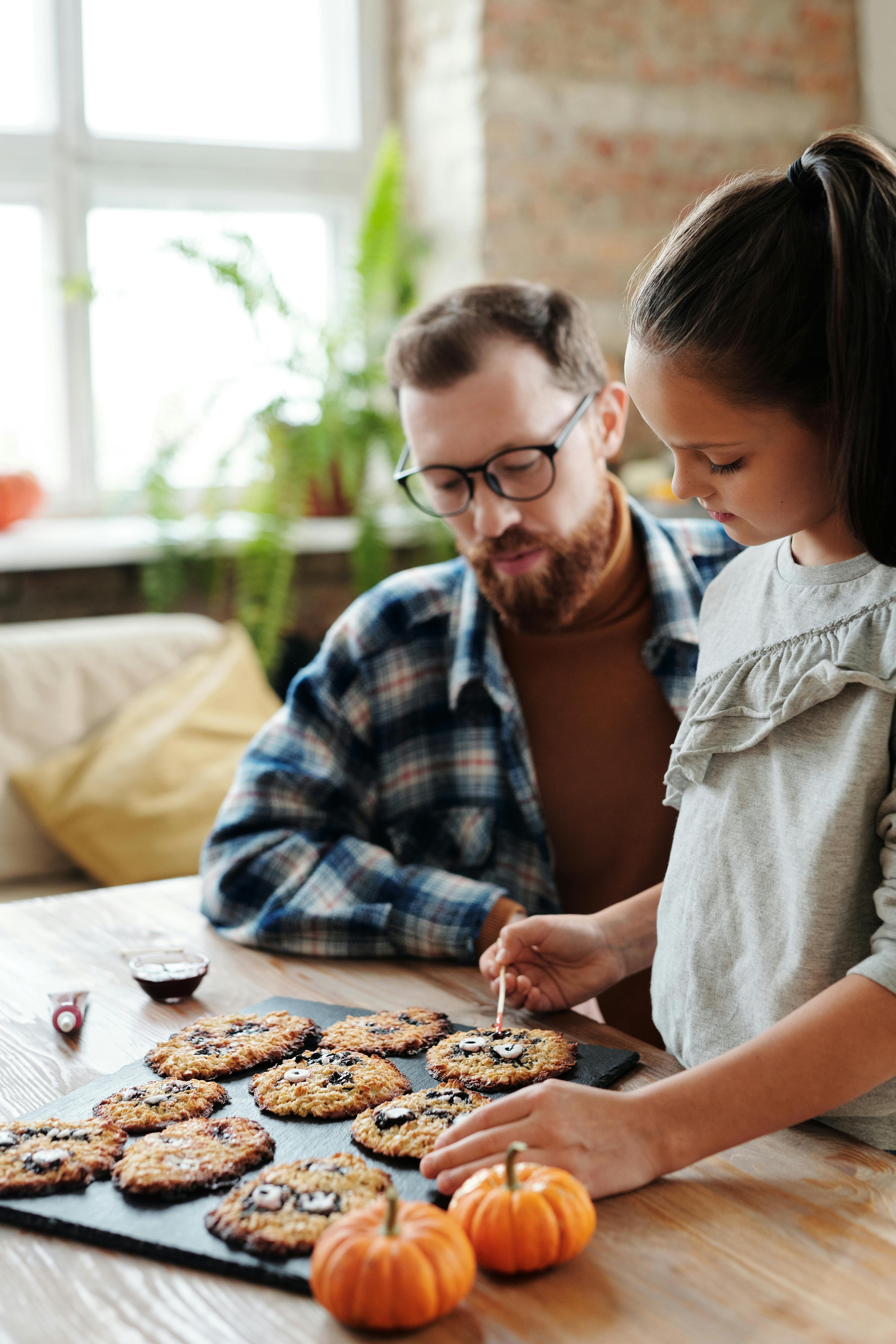 a girld decorating cookies with her father