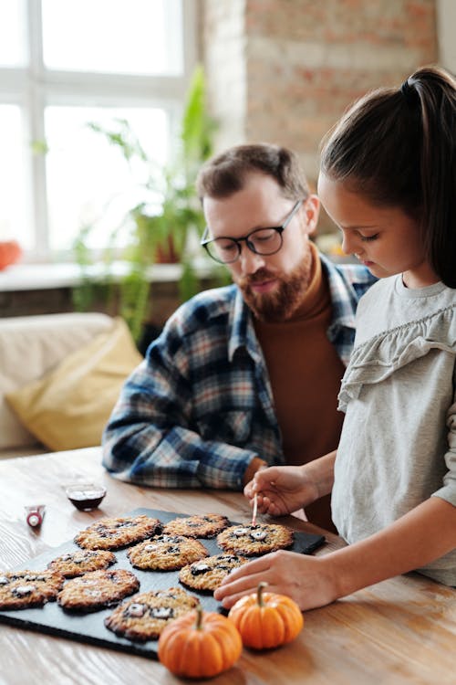 Девушка украшает печенье со своим отцом