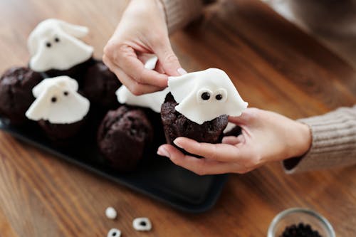 Personne Tenant Un Petit Gâteau Au Chocolat Avec Glaçage Blanc Sur Le Dessus