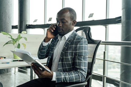 Free A Man Talking on the Phone while Sitting on a Chair Stock Photo