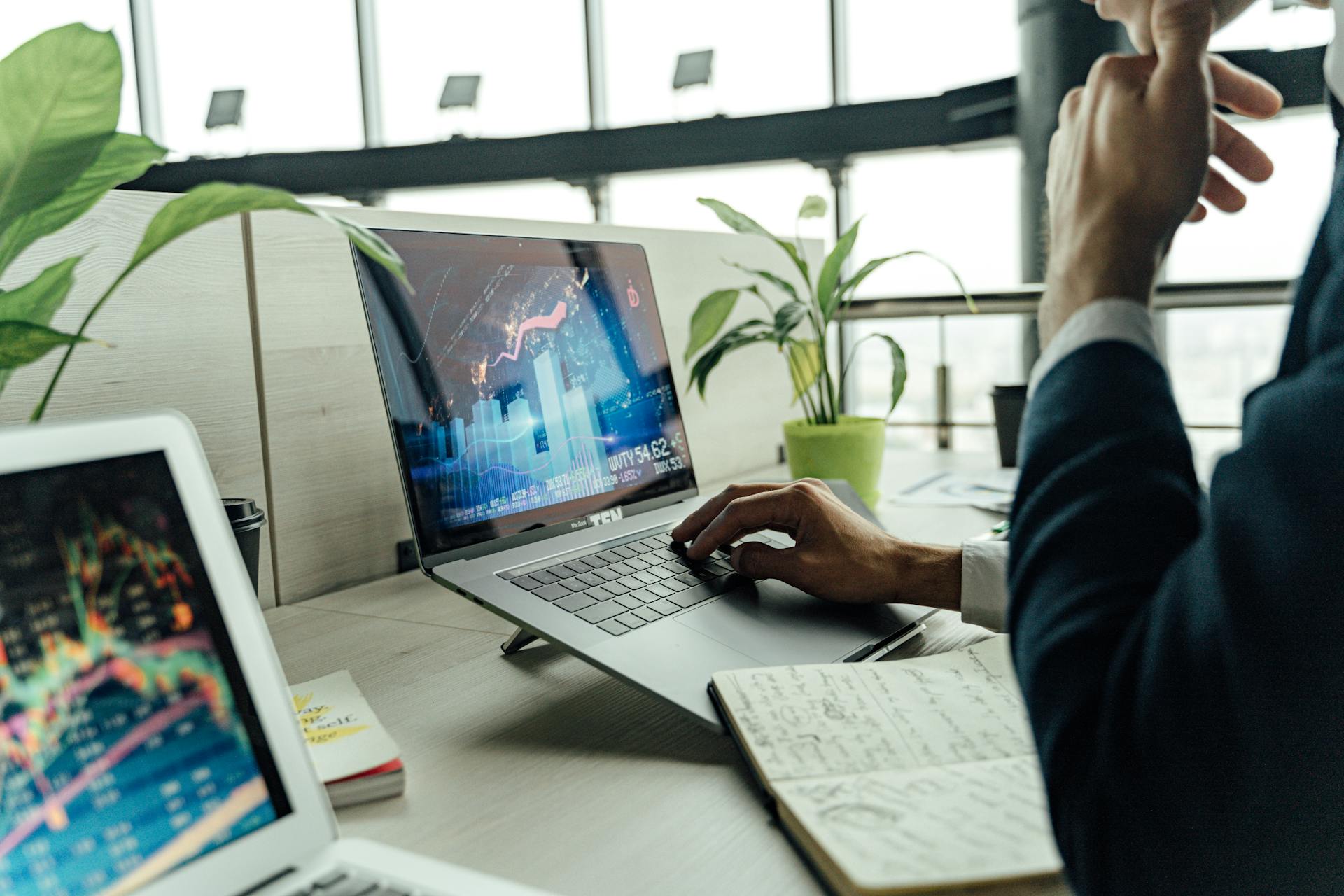 A professional analyzing stock market data on a laptop in a bright office environment.