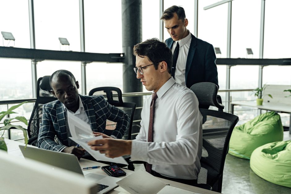 Professionals engaging in teamwork and discussion in a contemporary office setting with large windows. Professionals engaging in teamwork and discussion in a contemporary office setting with large windows.