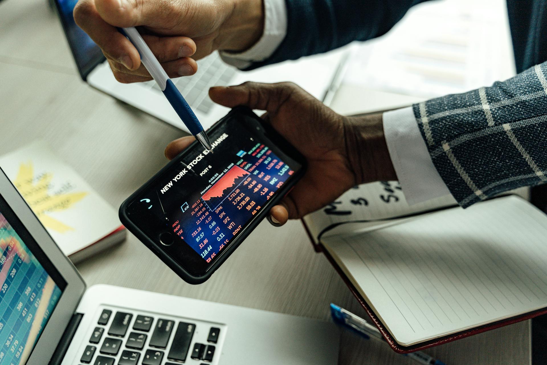 Business professionals analyzing stock exchange data on a smartphone in an office setting.