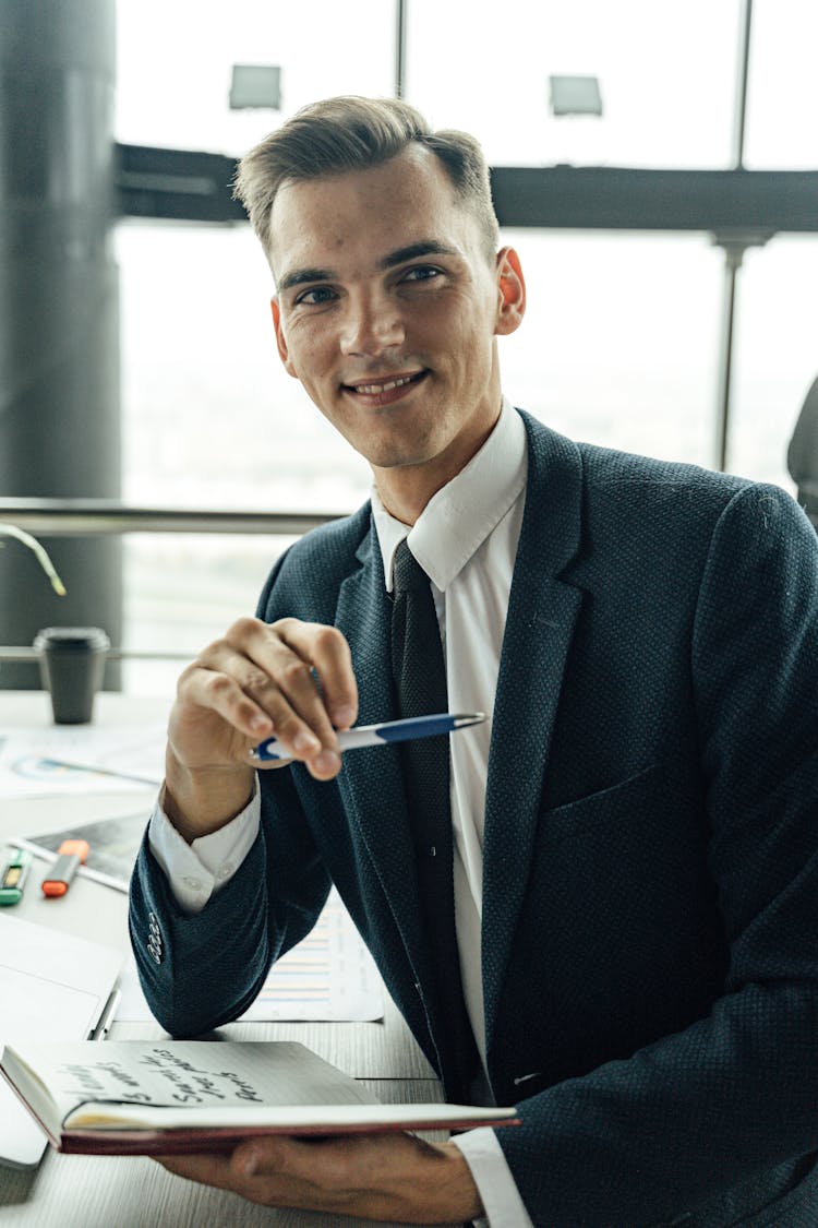 Man In Black Suit Holding Pen And Notebook