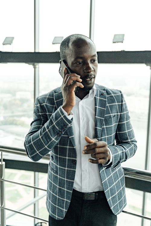 Free A professional man engaged in a phone call in an urban high-rise office with a glass facade. Stock Photo