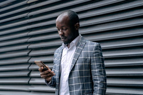 Man in Plaid Coat Using a Smartphone
