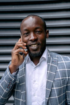 穿着格子夹克的商人在户外微笑着用智能手机交谈