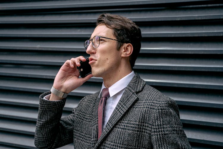 A Man In Checkered Suit Talking On The Phone