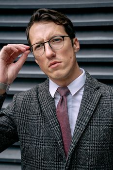 一位时尚男子穿着格子夹克，在户外调整眼镜的肖像