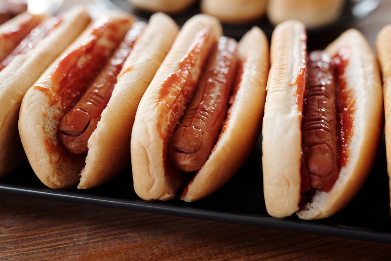 Row of hot dogs with ketchup on a tray