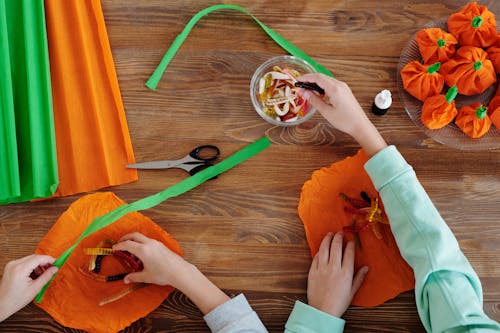 Дети упаковывают конфеты в оранжевую бумагу