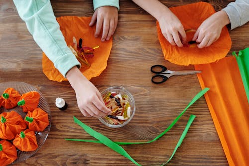 Дети упаковывают конфеты в оранжевую бумагу