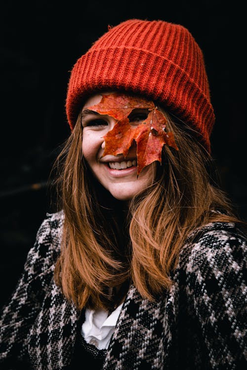 A Happy Woman in Red Knit Cap with a Maple Leaf on Her Face
