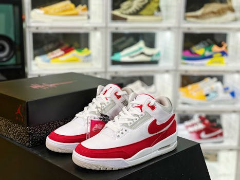 A pair of stylish red and white sneakers displayed with a branded sneaker box in a shoe store.