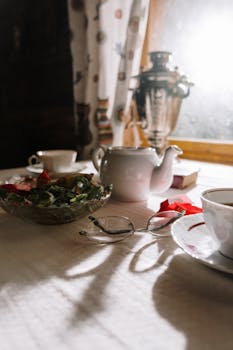 Warm indoor scene featuring a teapot, glasses, and a samovar on a sunlit table.