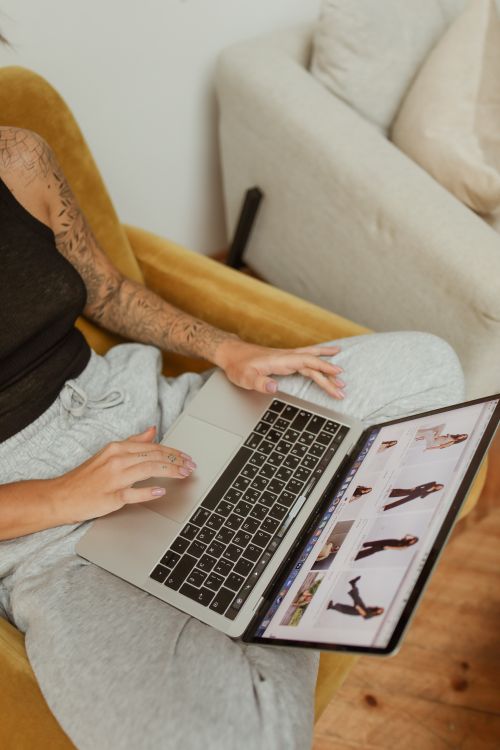 Free A tattooed woman using a laptop for online shopping while sitting in a cozy indoor setting. Stock Photo