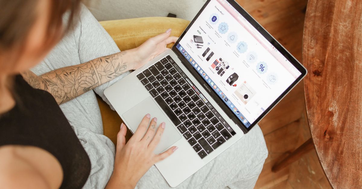 Woman with tattoos browsing online shopping site on a laptop indoors