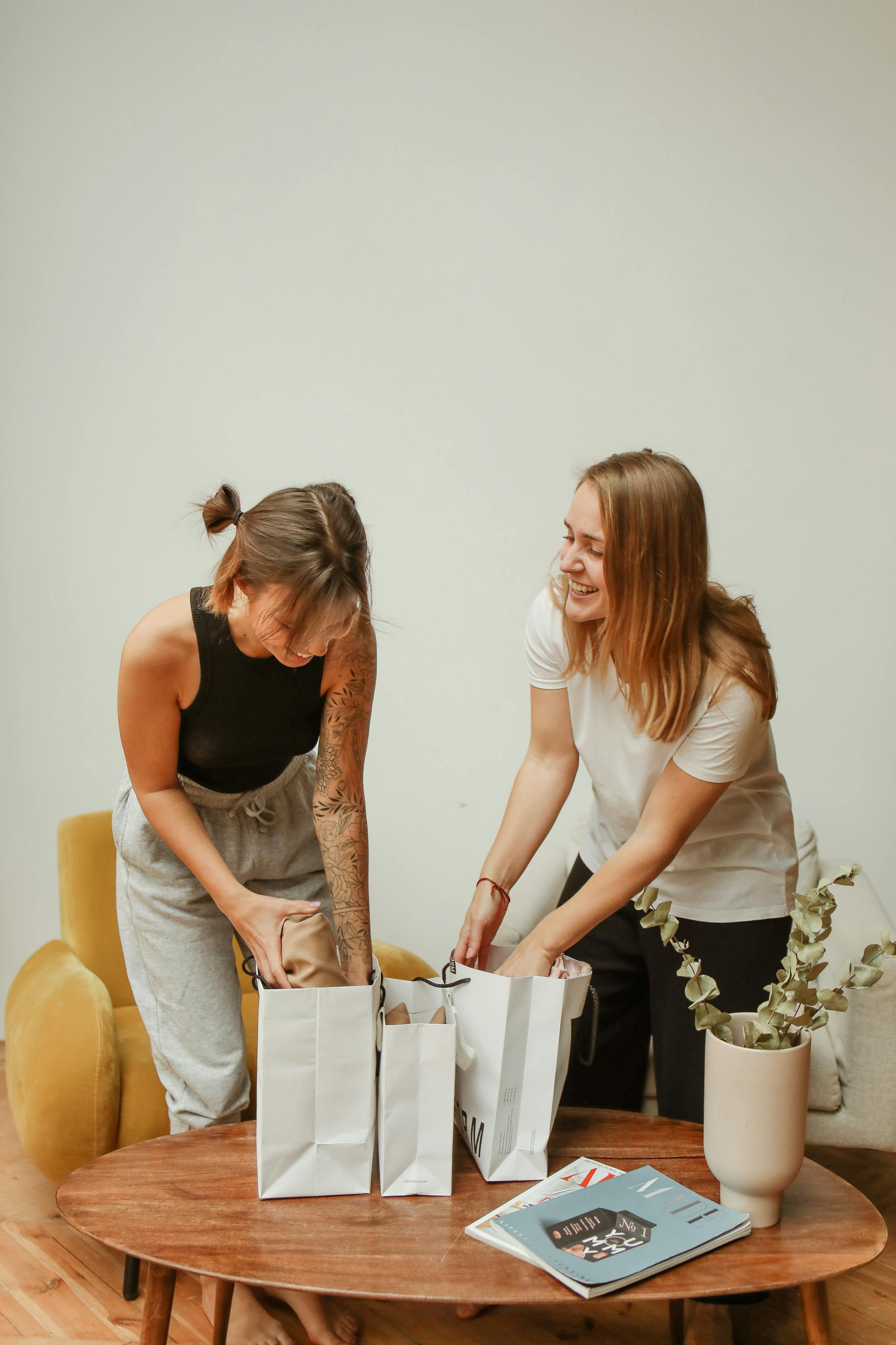 两名年轻女子在家中愉快地打开购物袋，共享快乐的拥抱时刻