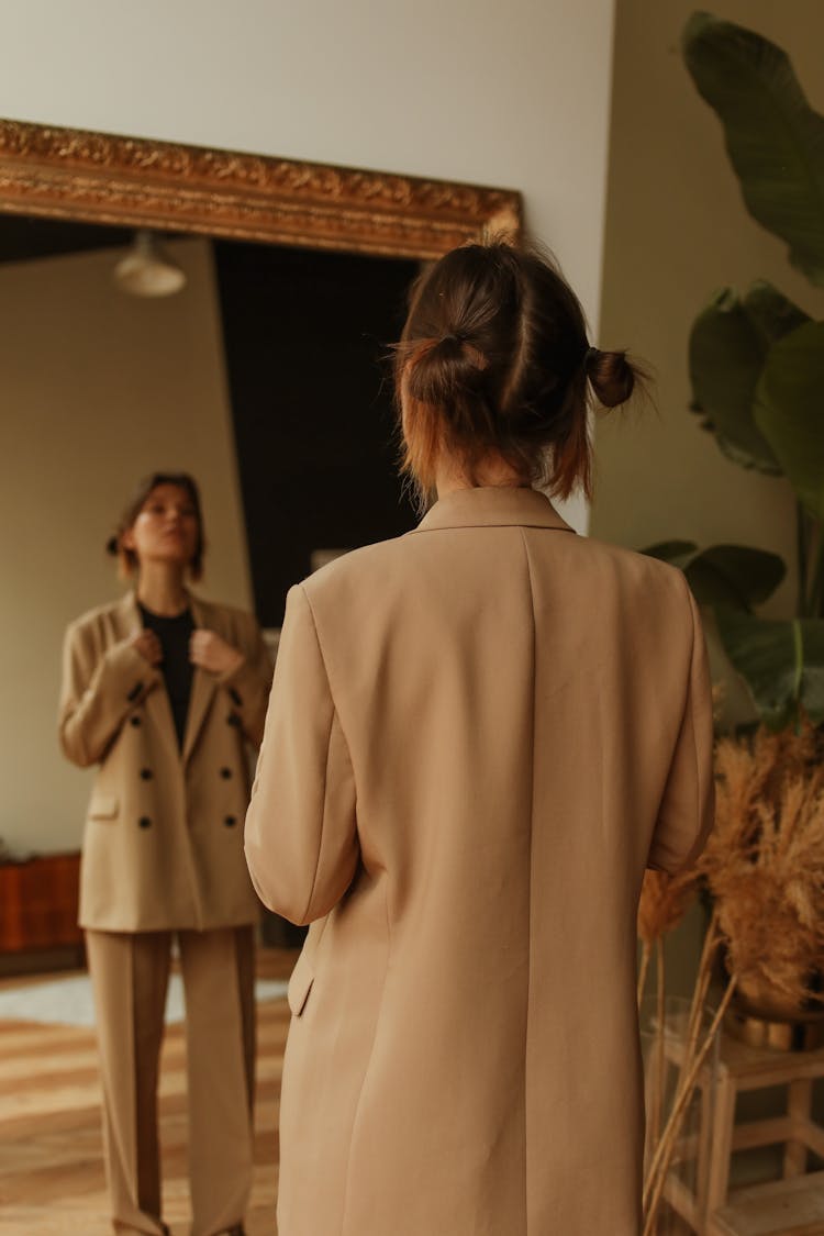 A Woman In A Suit Looking At A Mirror