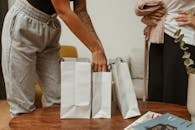 Person in Gray Pants with Hand Inside White Paper Bag