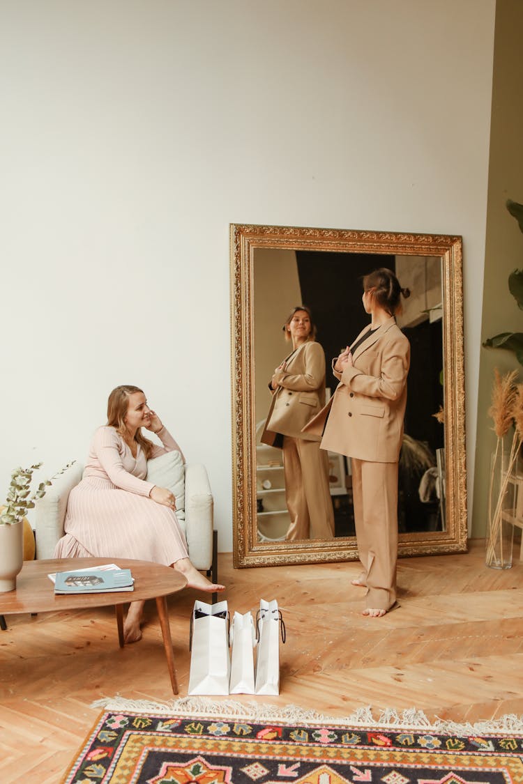 Woman In Brown Suit Looking At Self In Front Of Mirror