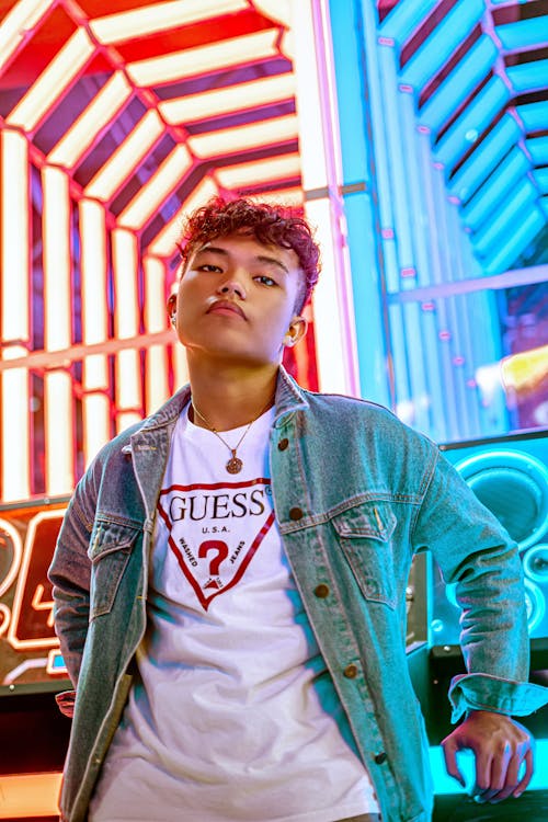 Boy in Blue Denim Jacket Near Blue and Red Illuminated Background
