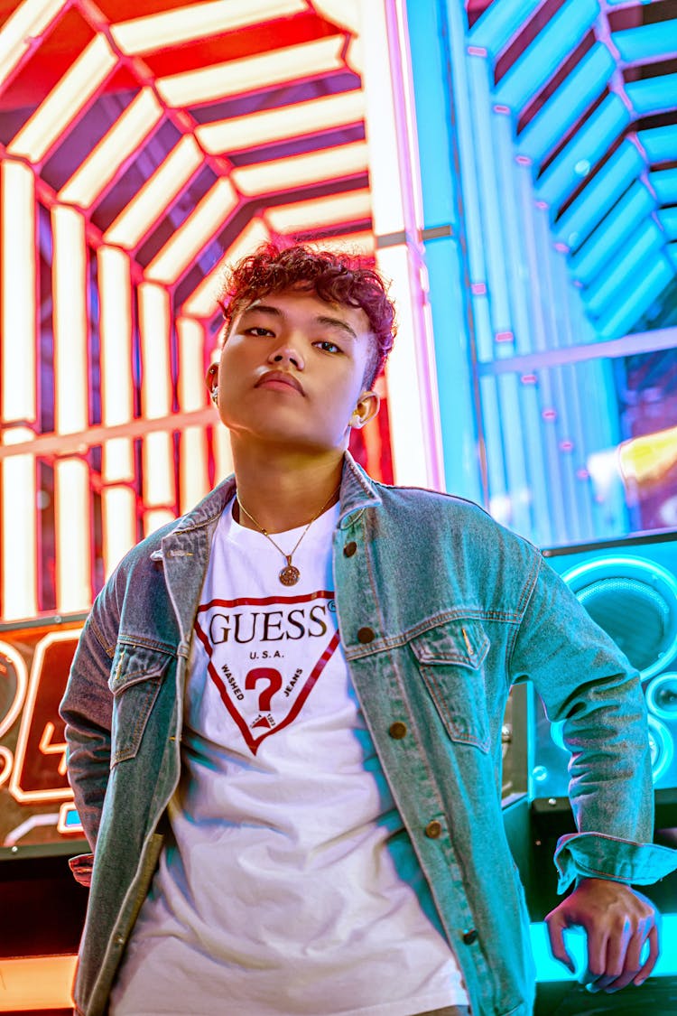 Boy In Blue Denim Jacket Near Blue And Red Illuminated Background
