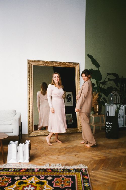 Free Two women posing in a modern room with a large mirror and elegant decor. Stock Photo