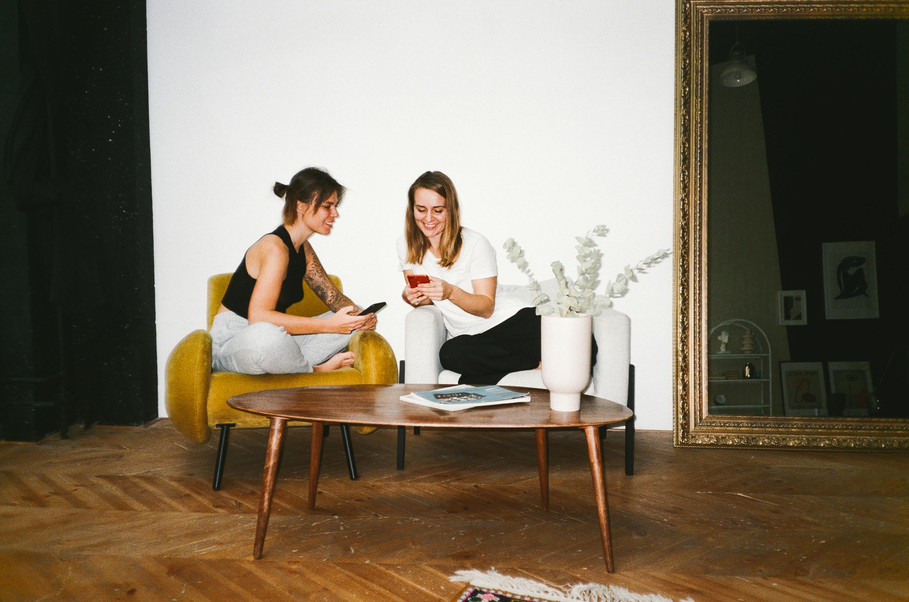 women using their smartphones while sitting on chairs