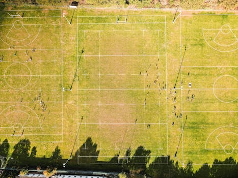 Drone shot of rugby fields in Cobham, England with people playing on grass.