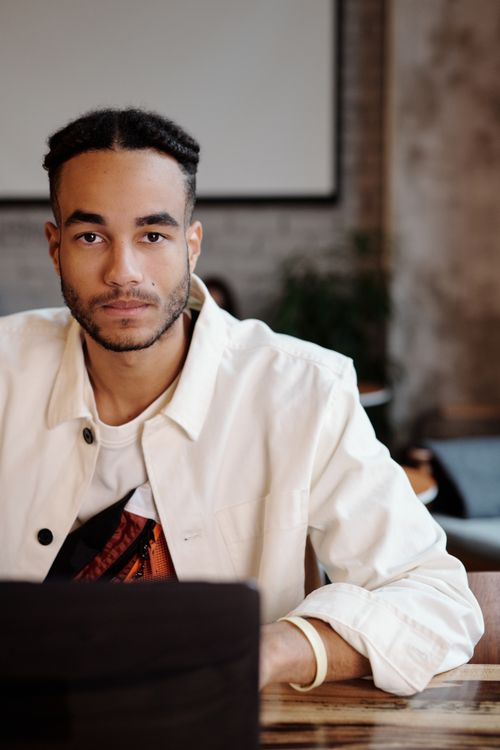 Free Handsome man in a white jacket working with a laptop in a trendy café. Urban and contemporary. Stock Photo