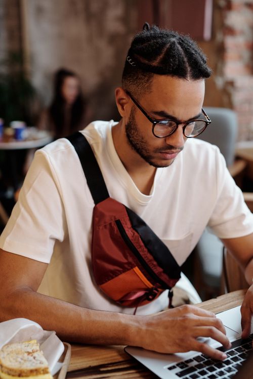 Free Focused young man freelancing on his laptop in a cozy café environment. Stock Photo