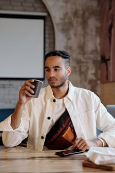 Young man relaxing in a modern cafe with a cup of coffee and a smartphone on the table.