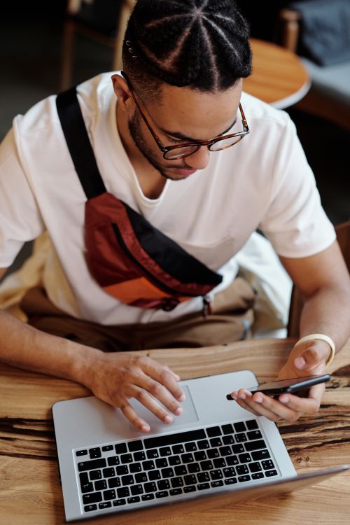 Free Focused man multitasking with laptop and smartphone in a cozy cafe setting. Stock Photo