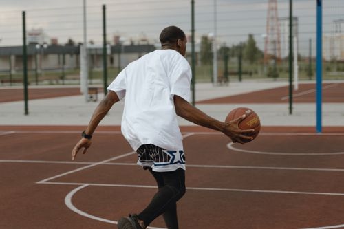 Free Athlete dribbling a basketball during an outdoor game on a sunny day. Stock Photo