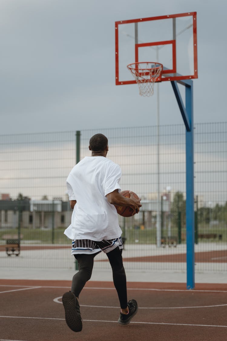 A Man Running While Holding A Basketball