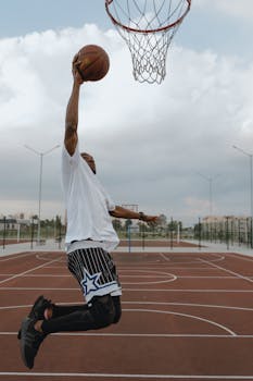 A stunning capture of an athlete in midair dunking on an outdoor basketball court.