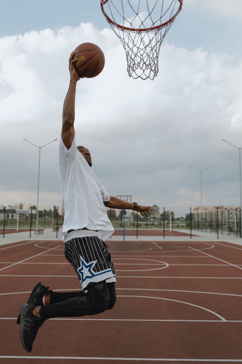 Athlete captured mid-air dunking on an outdoor basketball court