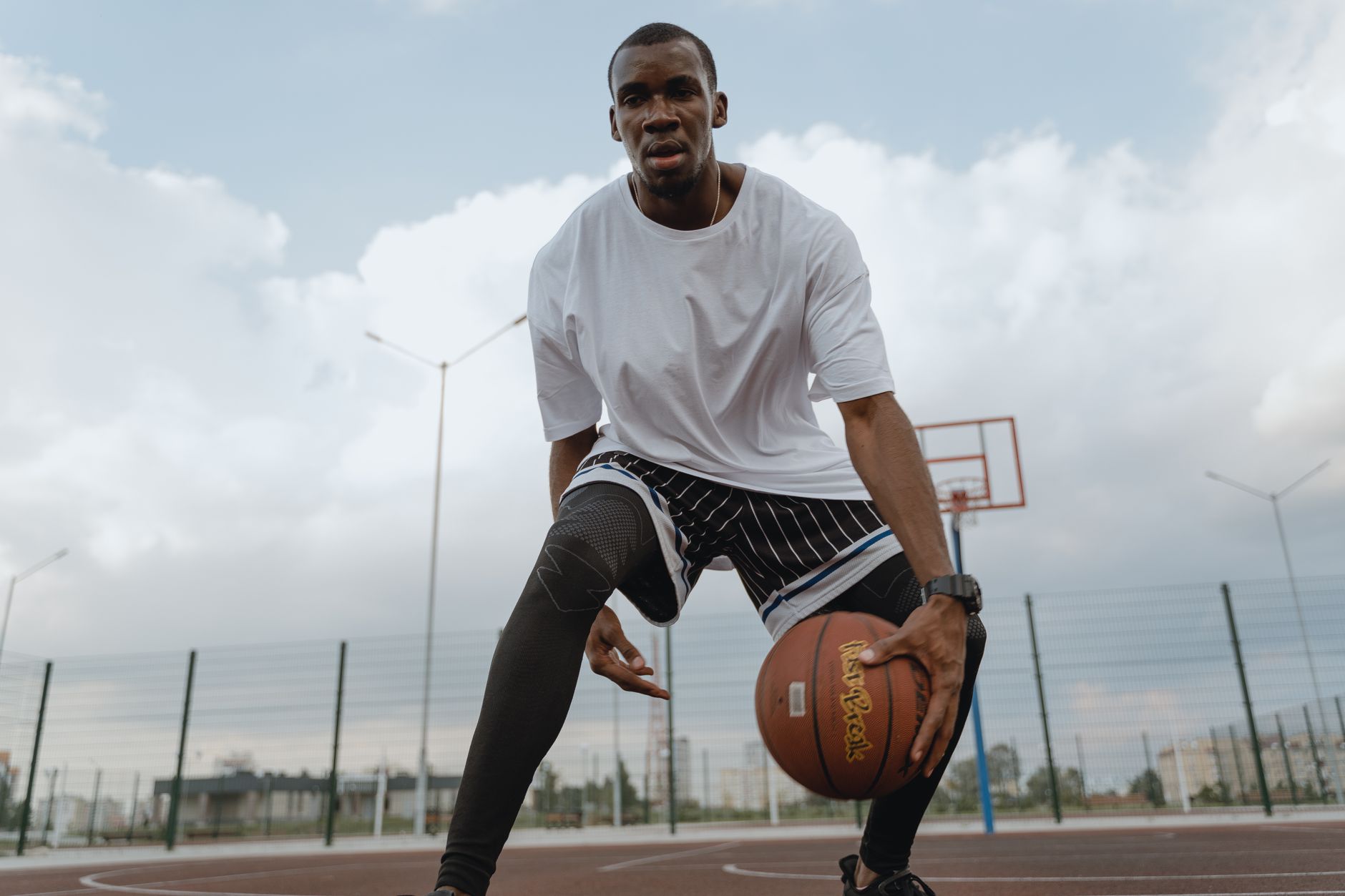A focused athlete dribbles a basketball on an outdoor court, embodying fitness and agility.