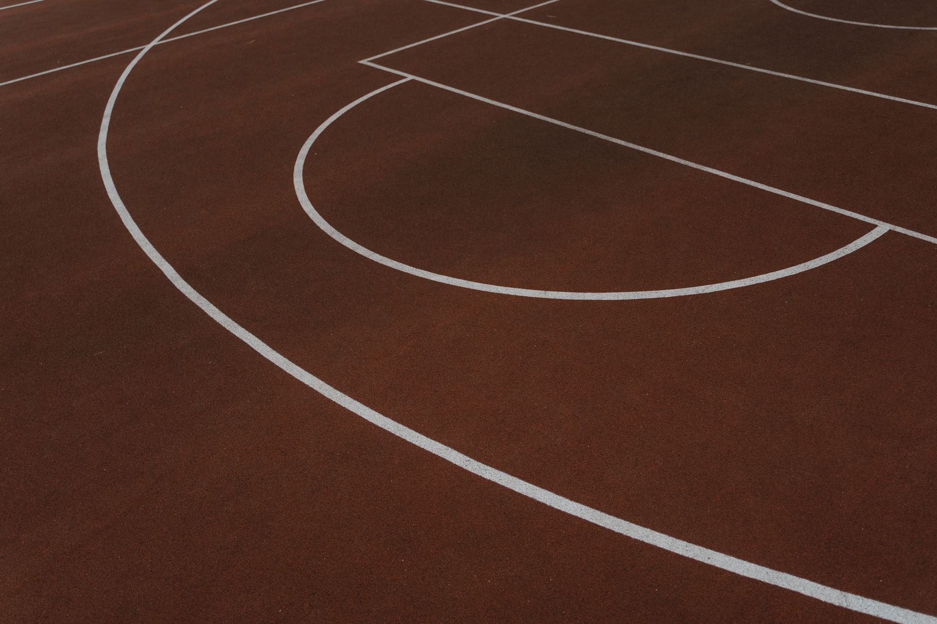 A detailed overhead shot of a brown basketball court with white lines.