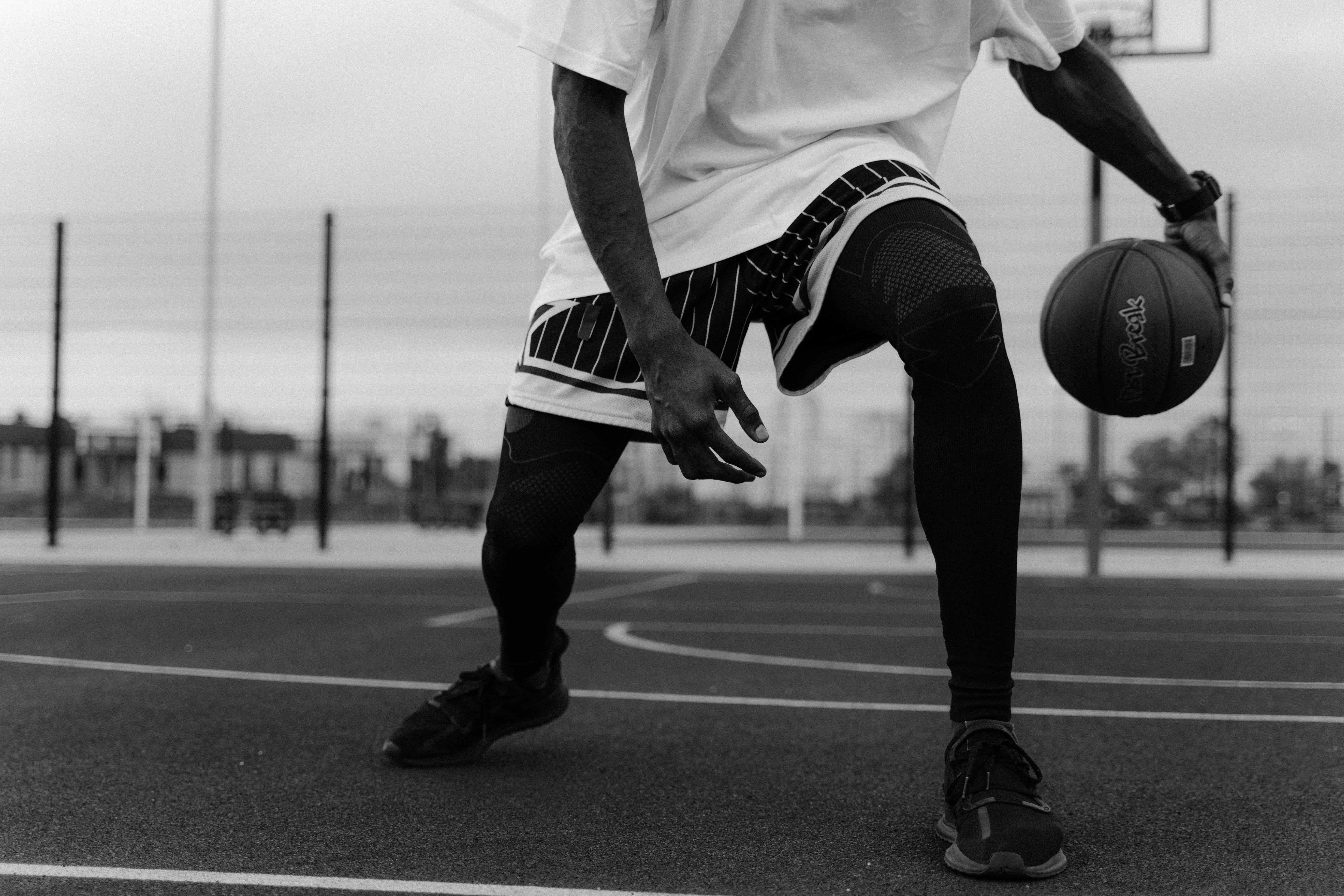monochrome photo of man playing basketball