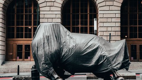 Covered statue of Charging Bull on Wall Street, New York City, symbolizing market volatility.
