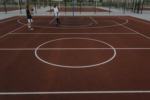 Two People Playing Basketball on Basketball Court