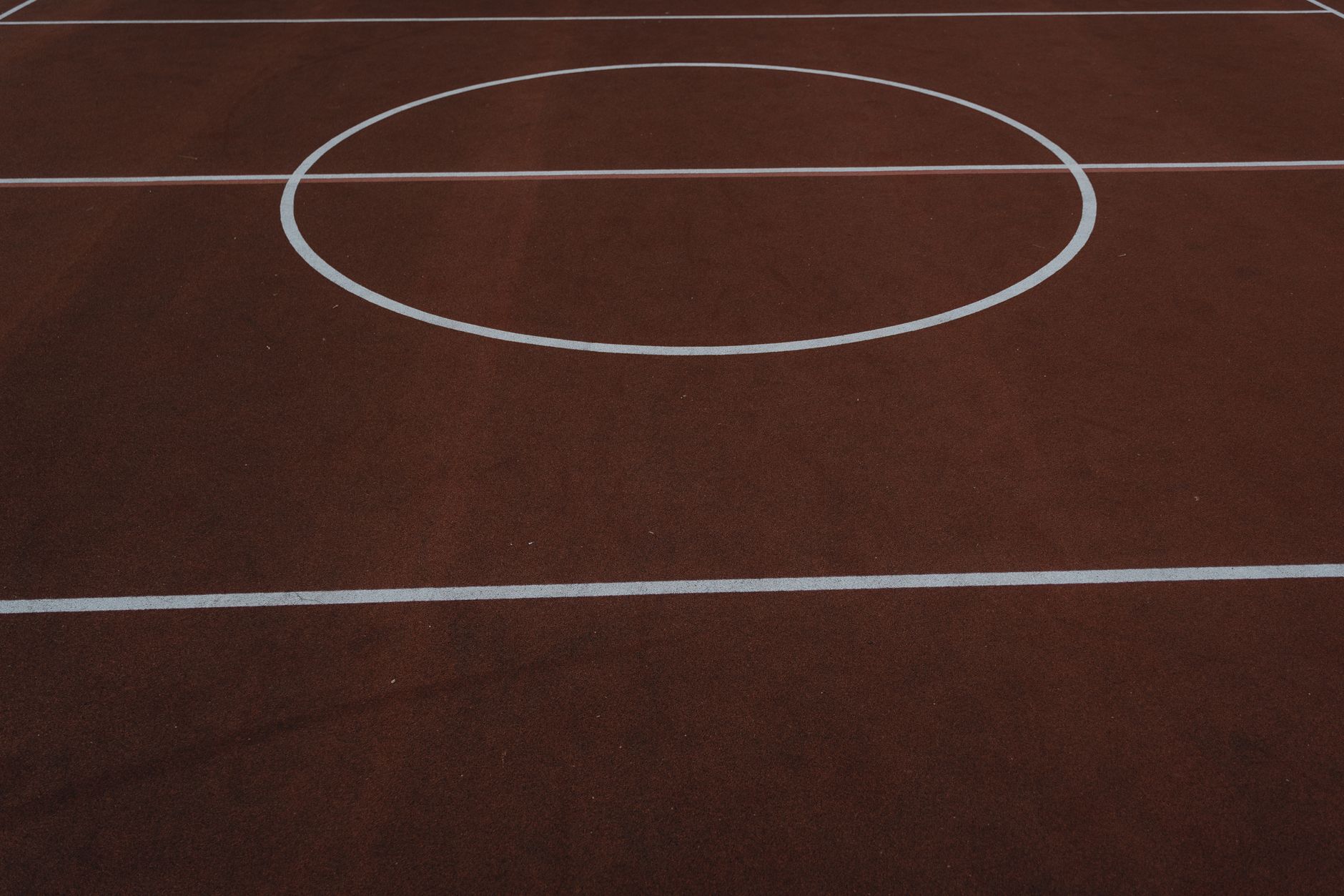 Aerial view of a basketball court featuring clean lines and a minimalist brown surface.