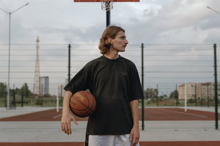 Man In Black Crew Neck T-shirt With Basketball Between His Arm And Waist